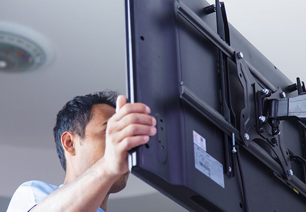 A person installing a television in a room